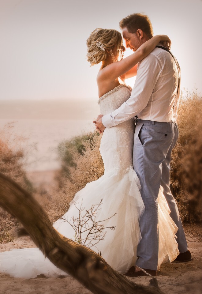 Bride and groom embrace on the shore line beach of the gecko beach club Ibiza at sunset golden hour