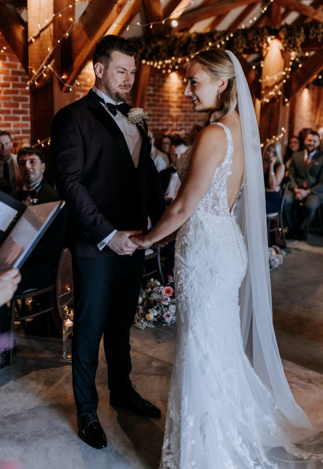 Bride and groom hold hands during their barn wedding ceremony in Kent