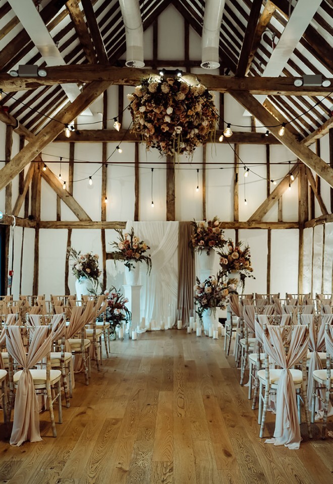 Wedding ceremony inside barn at Alfriston Gardens in East Sussex