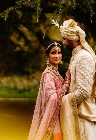 Bride and groom in traditional Hindu wedding outfits in the gardens of voco St Johns in Solihull