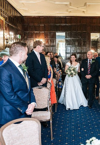 Bride walking down the aisle at Bisham Abbey. Berkshire