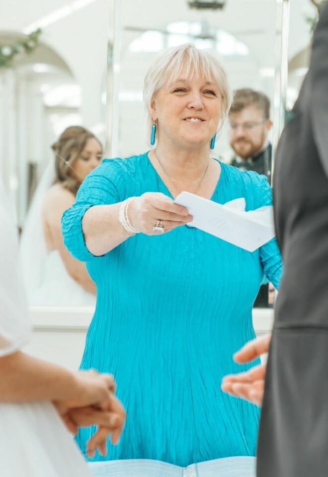 smiling celebrant hands groom his vows to read