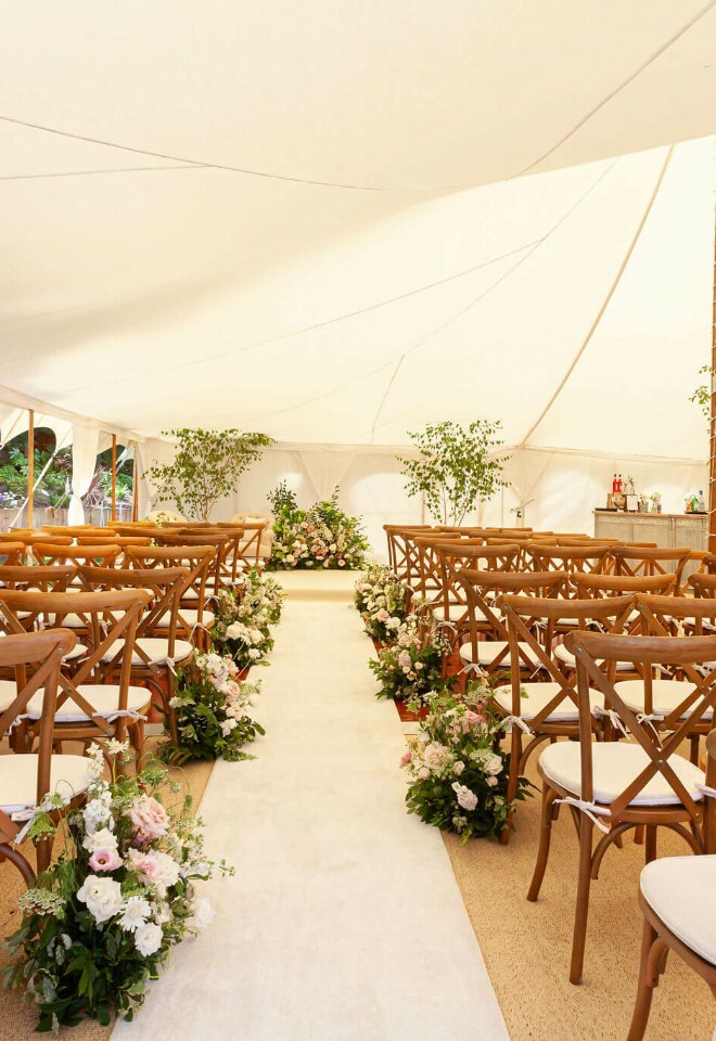 Soft pastel themed luxury marquee wedding in the garden of a London home. Indoor plants and an empire chandelier
