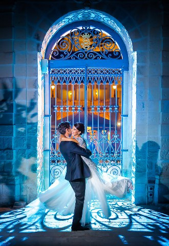 Groom lifts bride in front of beautiful garden gate