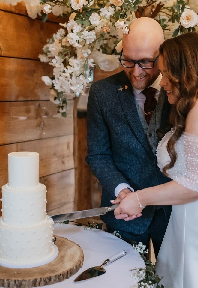 3 tier white wedding cake being cut by the bride & groom at burlton manor weddings shropshire west midlands