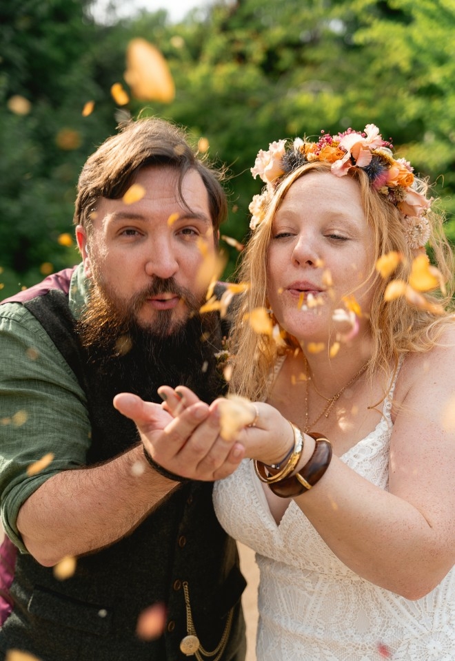 Groom and Bride blowing confetti from their joined hands