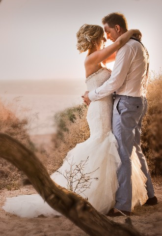Overseas Wedding with bride and groom embracing on Ibiza beach at sunset