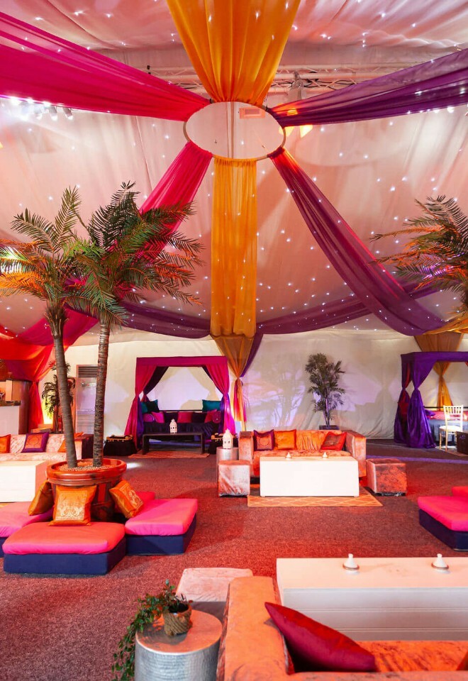 Luxury marquee with draping, palm trees and floor seating for an Asian wedding