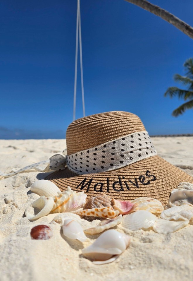 Personalised Maldives honeymoon by Not Just Travel James & Natasha, with a personalised sun hat on a tropical white sand beach