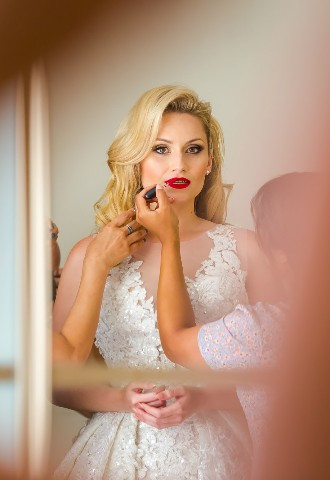 bride with her makeup artist getting ready on her wedding day morning