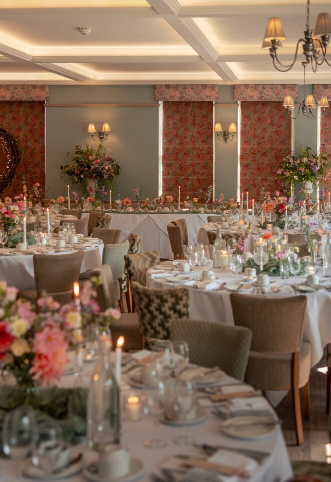 Elegant wedding breakfast setup at Washingborough Hall Hotel, with round tables, floral centrepieces, candles, and a heart-shaped decoration in the background.