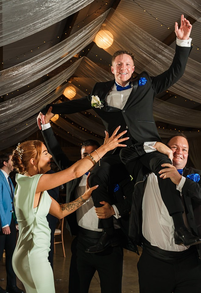 Groom being lifted onto groomsmans shoulders