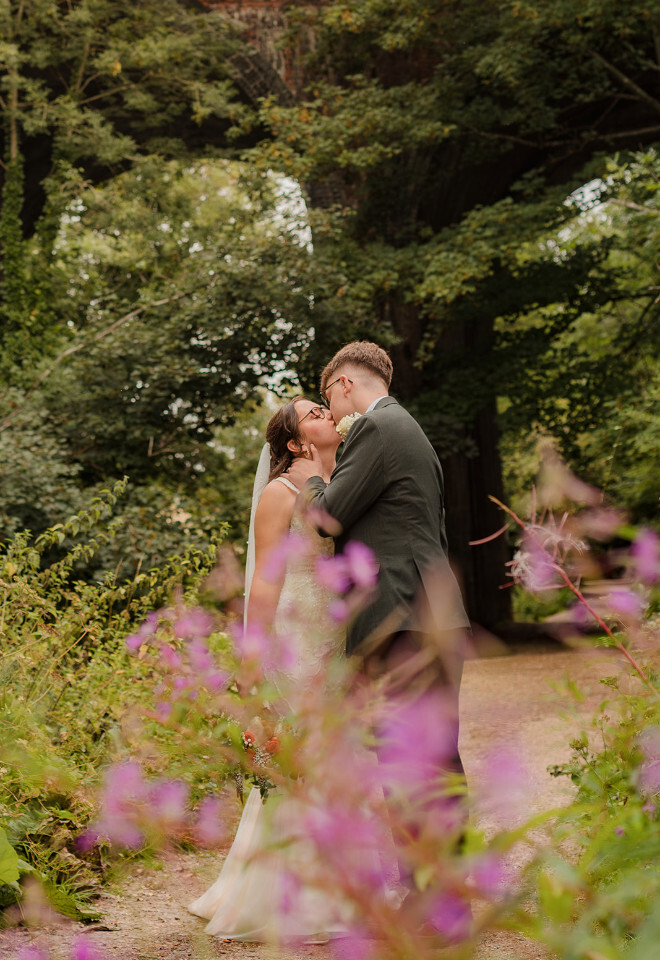 “Bride and groom sharing a kiss in a garden setting at a wedding at Basingmill in Basingstoke photographed by Katy Brothers Wedding Photography”