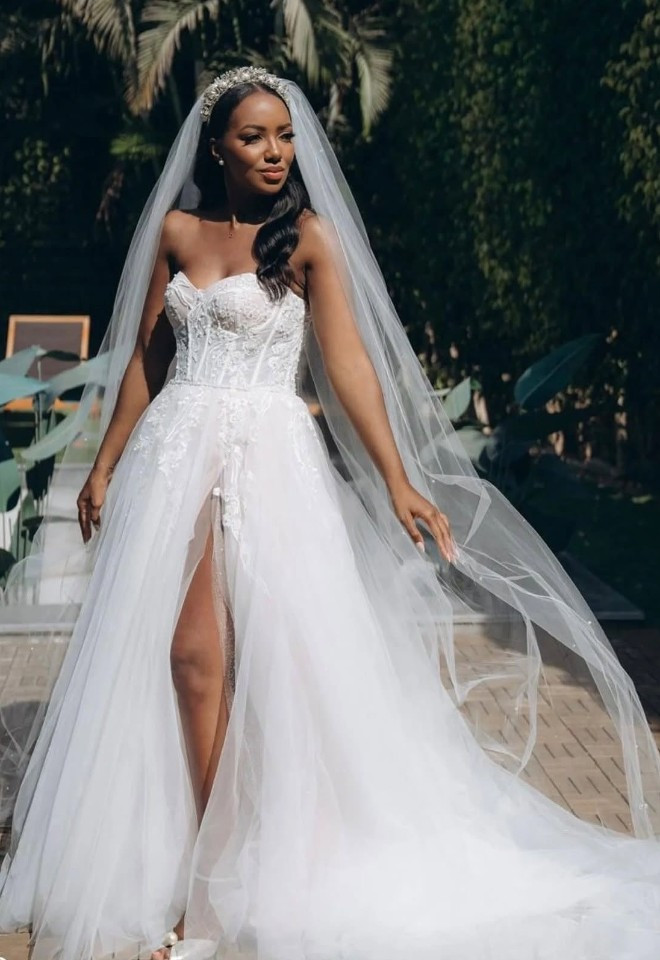 Our real bride wearing a strapless lace wedding dress by Riki Dalal, with a fitted bodice, full tulle skirt, high split and long veil, available at Little London Brides in Hampshire.