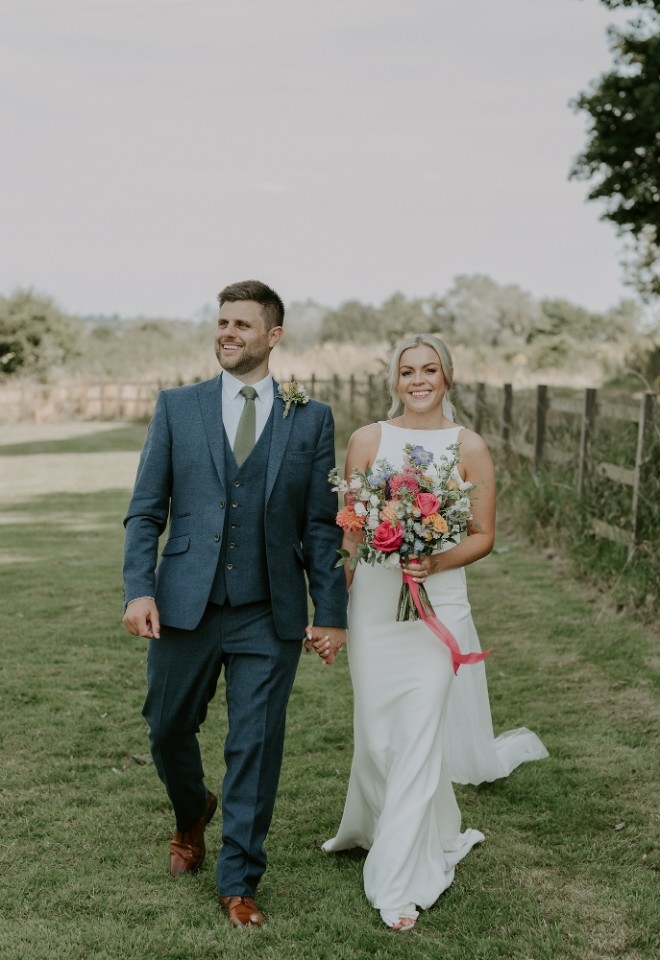 Wedding couple walking through the vineyard at Copdock Hall wedding venue in Suffolk