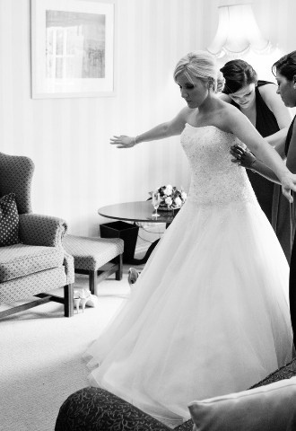 Bridesmaids help bride put on her dress