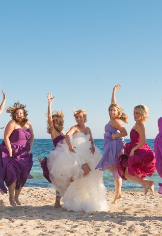 Overseas Wedding photography Ibiza Wedding with bride and bridesmaids leaping in the air on beach