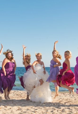 Overseas Wedding photography Ibiza Wedding with bride and bridesmaids leaping in the air on beach