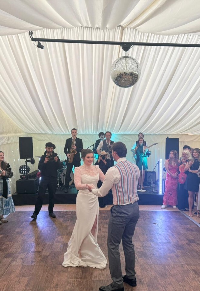 Bride and groom enjoying their first dance at a luxury marquee wedding reception, with live music, wedding guests and a beautifully styled celebration