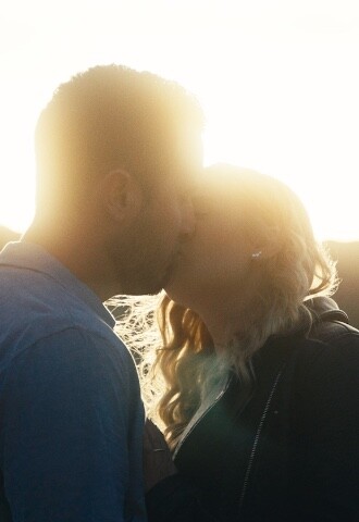 engaged couple kissing in sunset