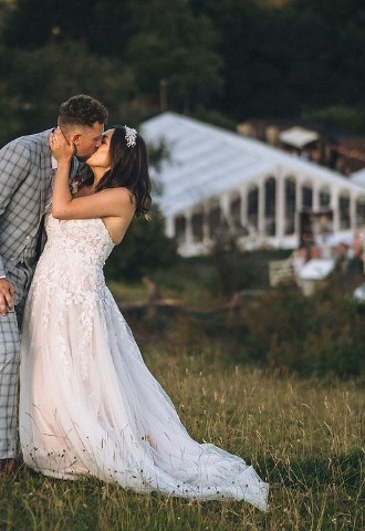 Wedding couple kissing in front of The Stables Wedding Farm