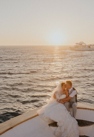 bride and groom pose at sunset on the end of a yacht in cyprus