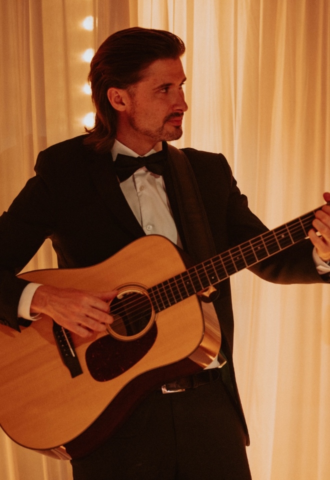 Suited man plays acoustic guitar