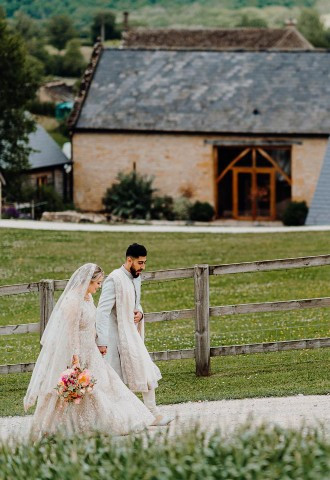 bride and groom walk past the wedding venue on their big day