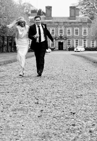 Black and white image of bride and groom walking away from the wedding venue and reception