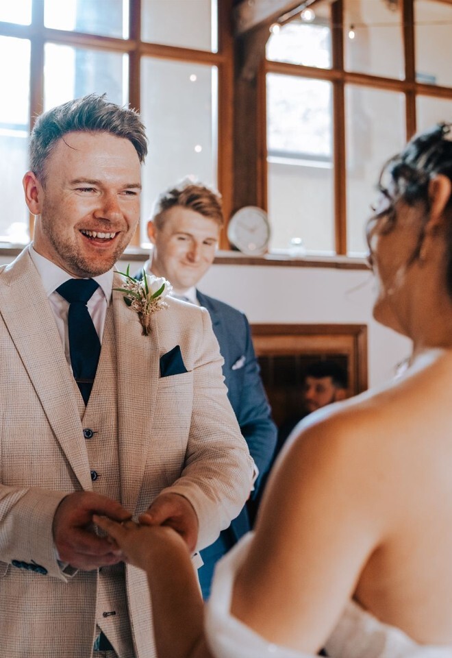 Happy groom exchanging rings with bride during celebrant wedding ceremony