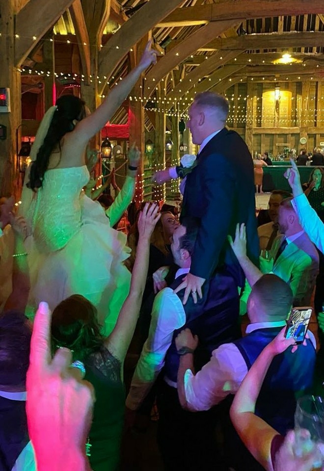 wedding reception with bride  & groom on the shoulders of their wedding guests as the live band from alive network agency create the best vibe