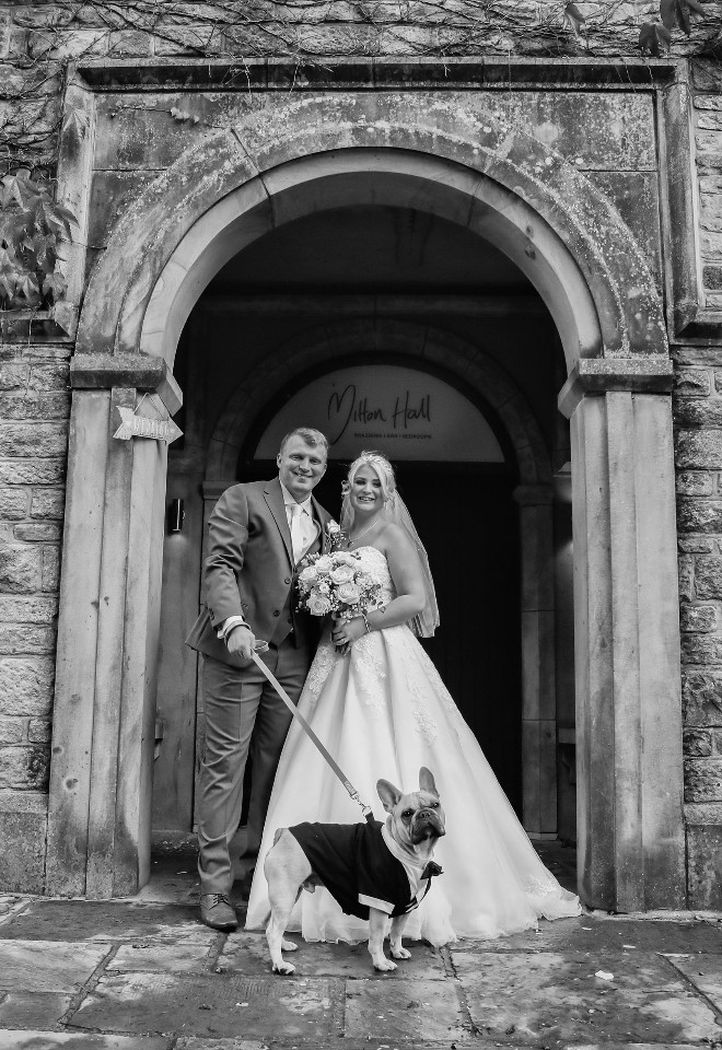 Mitton Hall wedding with bride & groom stood in the doorway with their french bulldog wearing a bestman suit, image in black & white