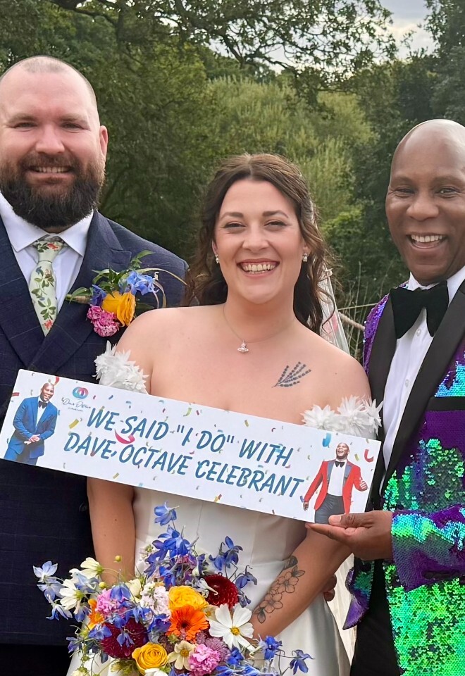 Dave Octave Celebrant with a happy bride and groom smiling and holding my We said I Do with Dave Octave Celebrant sign.