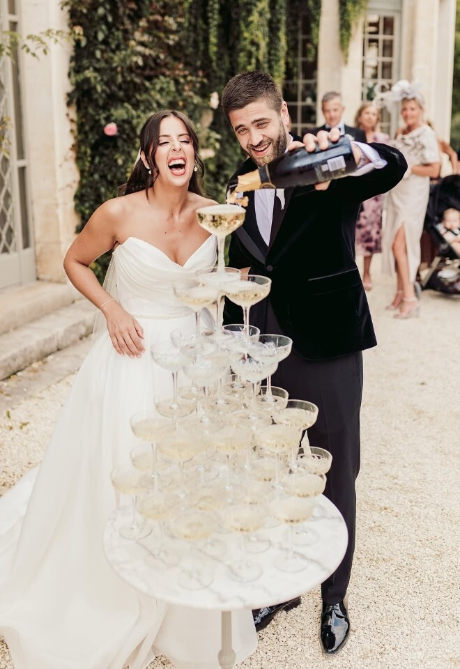 Couple poring champagne in to a champagne tower taken by Sam Rundle Photography, Essex