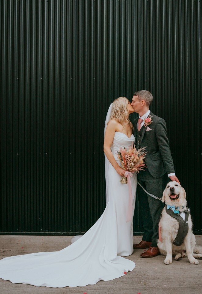 Couple posing with their dog in front of black metal background d
