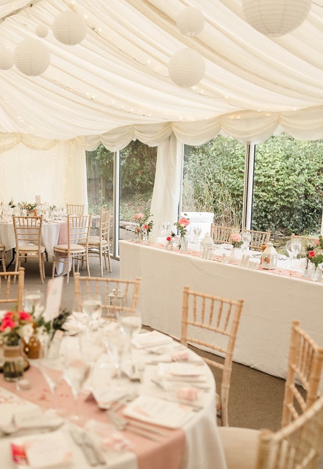 Wedding breakfast set up in The Cock O’Barton’s garden marquee, with dressed tables, soft pink details and Chiavari chairs.
