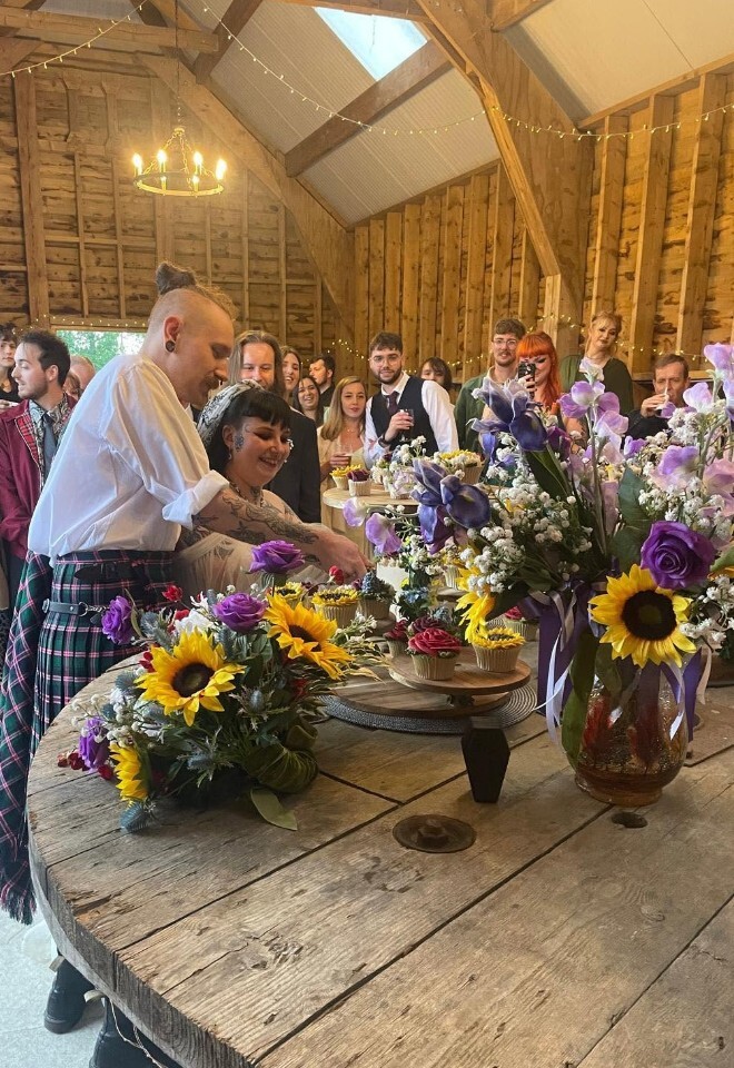married couple cutting the cake at Windsor Farm, Bosleys Farm, Wantage, Oxfordshire. floral display of sunflowers
