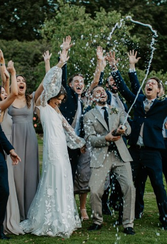 Bride, groom and their wedding party celebrate with champagne at Plas Dinam, Powys