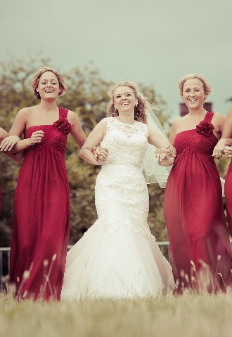 Bride walking with her bridesmaids in field behind wedding venue
