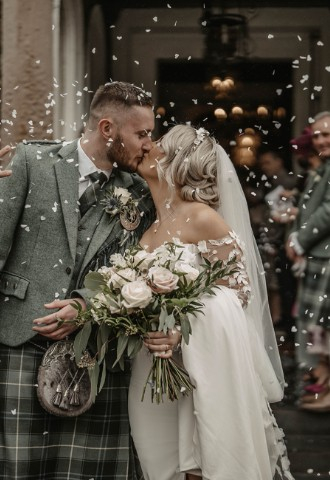 Bride and groom with confetti at Auchen Castle - a romantic castle wedding venue in Scotland
