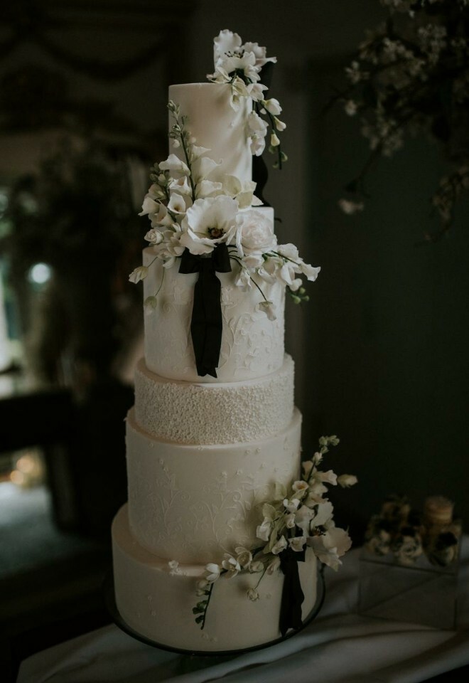 White and black tiered cake with sugar flowers and bows
