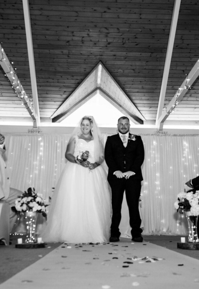 brides in white lace wedding dresses and Groome in a dark red suite during their wedding celebration with purple floral details.