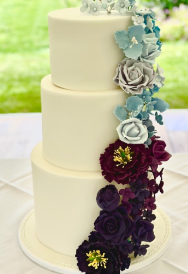 White Wedding Cake with Trailing Sugar Flowers in shades of Blue and Purple 