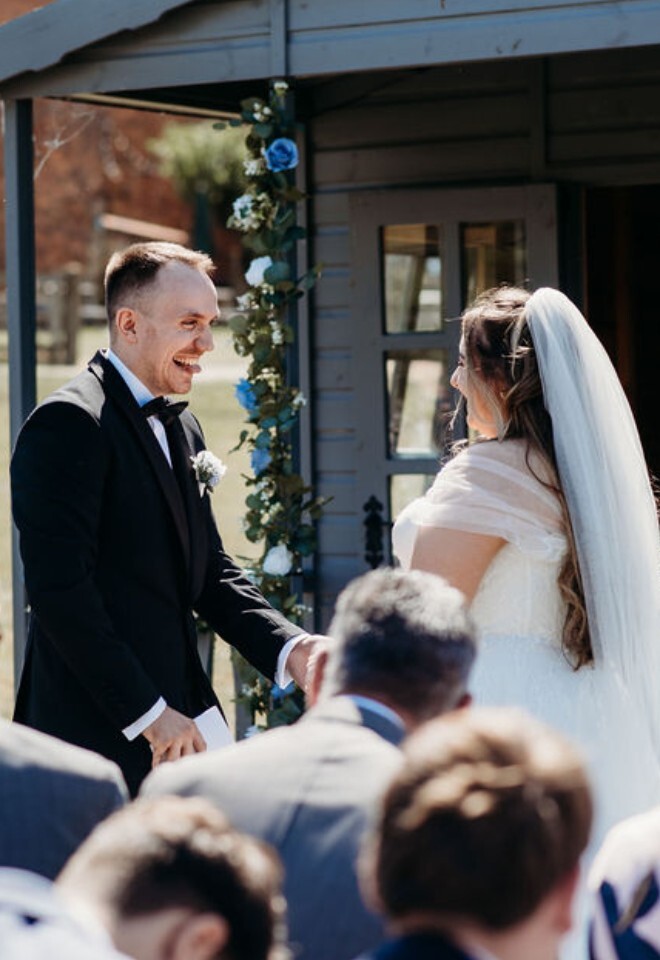 Groom sharing cheeky smile with bride during Buckinghamshire outdoor wedding ceremony