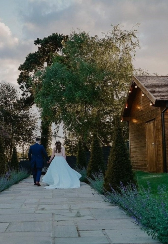 A bride and groom walking through the garden at an exclusive Warwickshire wedding venue