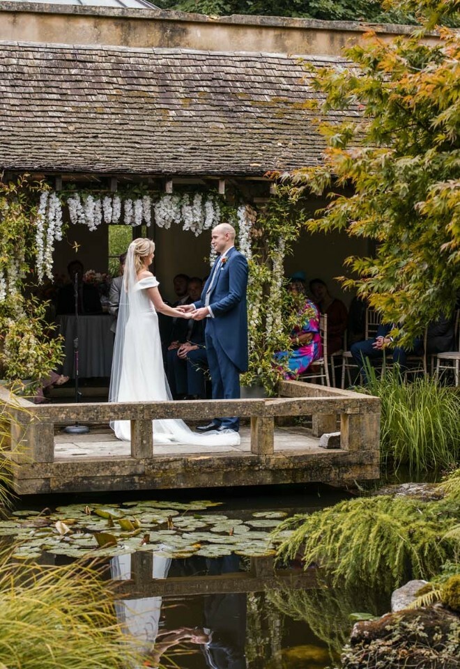 wedding couple holding hands near the pond