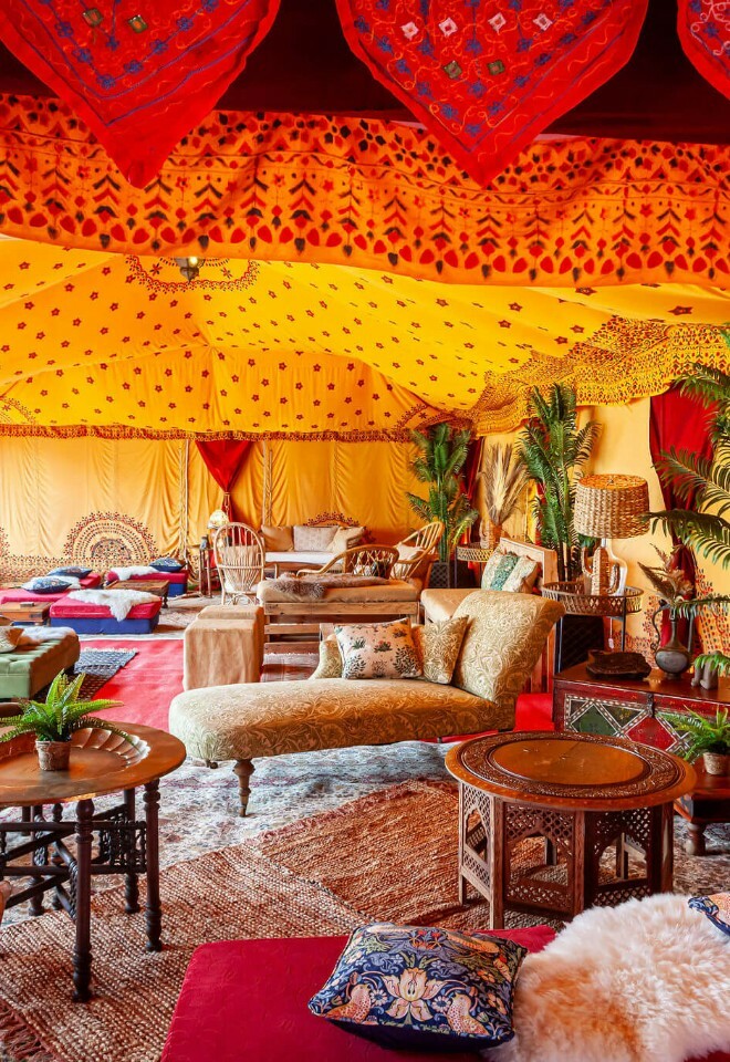 Luxury marquee with saffron linings filled with boho lounge furniture and potted palms