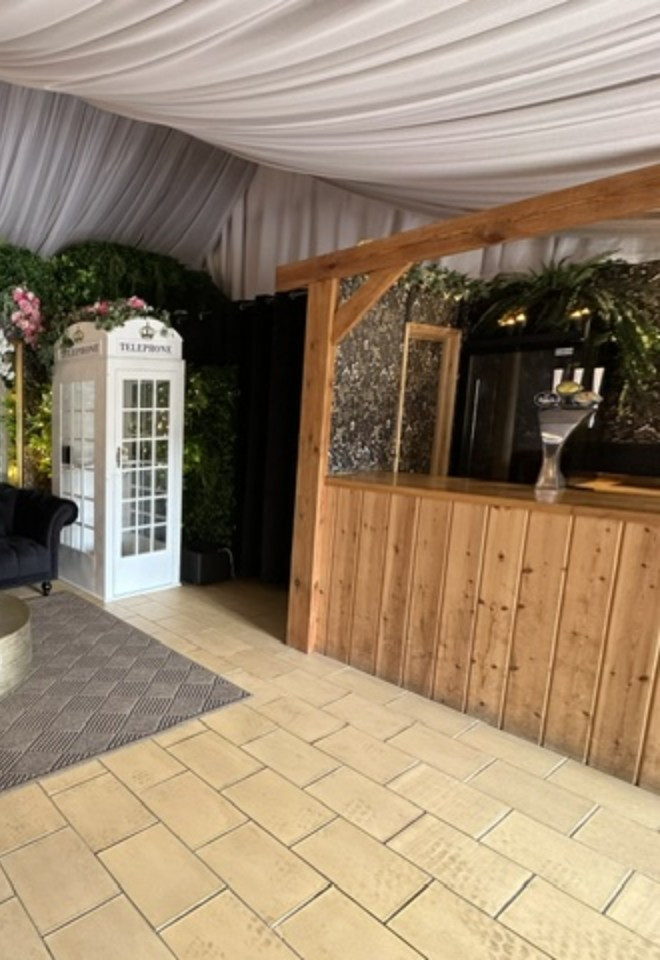Wedding lounge at Duvale Priory in Tiverton, Devon, with elegant seating, floral décor, a vintage telephone box and rustic wooden bar.