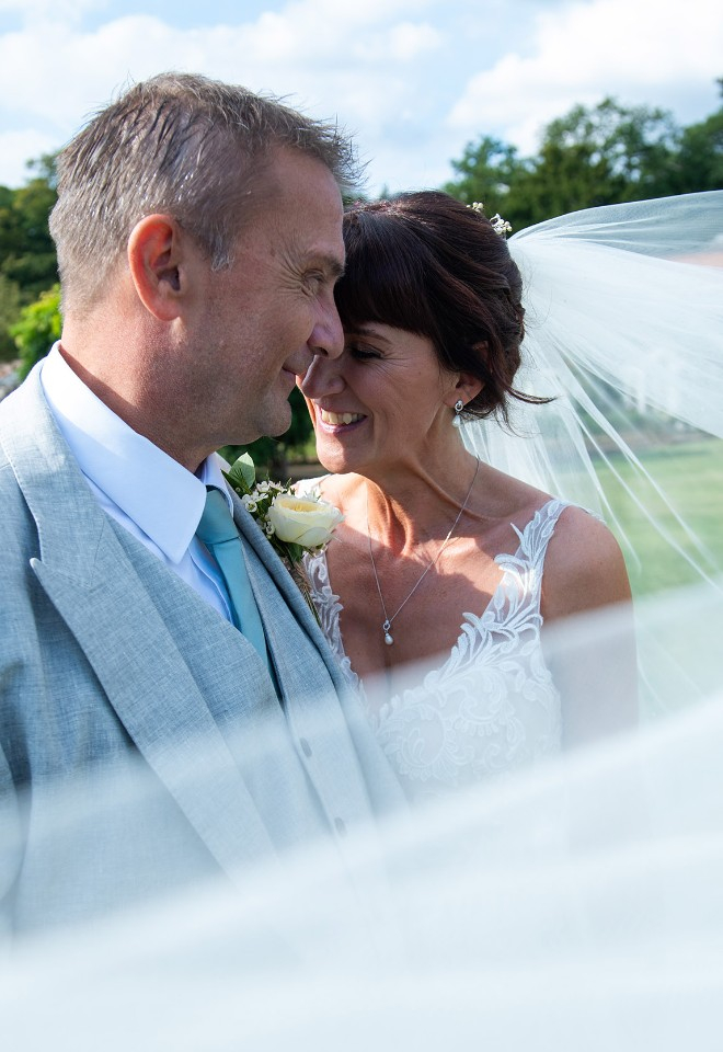 A brides veil swirls around the newlywed couple on their wedding day at Stapleford Park, Melton Mowbray