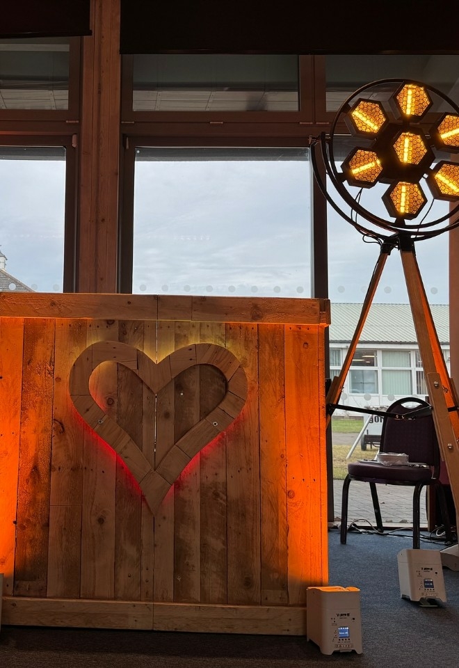 Wooden DJ booth with heart on the front with tall lights either side